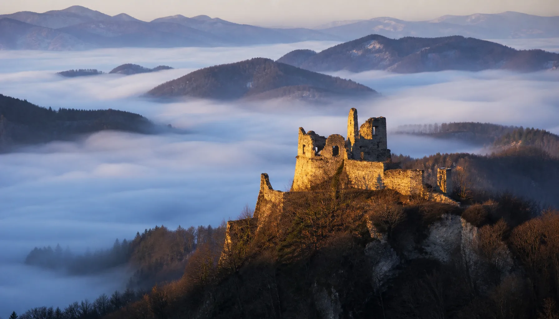 Dawn on the Považský Inovec — the ruin standing clear above a valley still full of mist