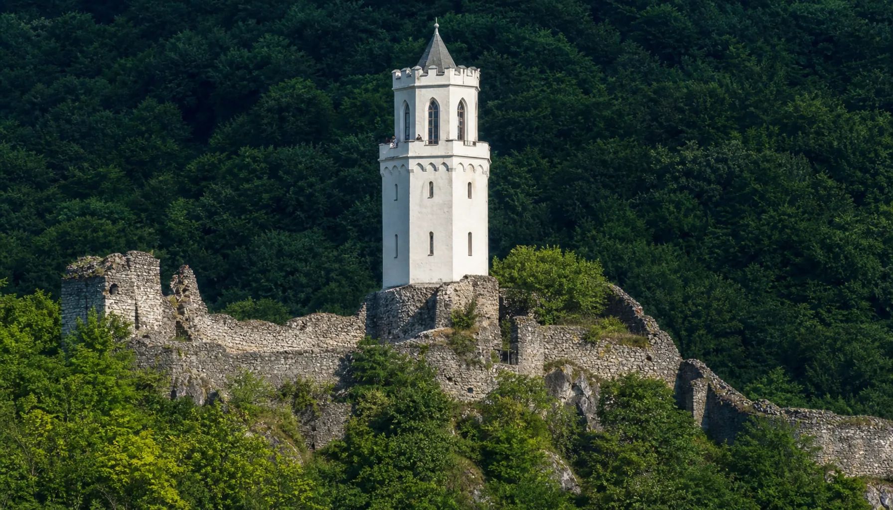 The slim white neo-Gothic lookout tower raised on the medieval ruin of Topoľčiansky hrad in the nineteenth century