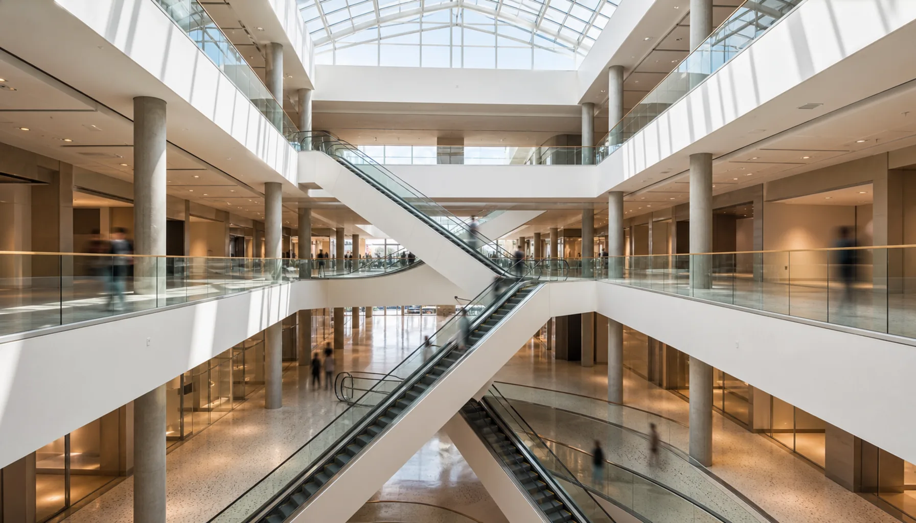 The central void with its stacked balconies and crossing escalators, daylight falling from the roof glazing