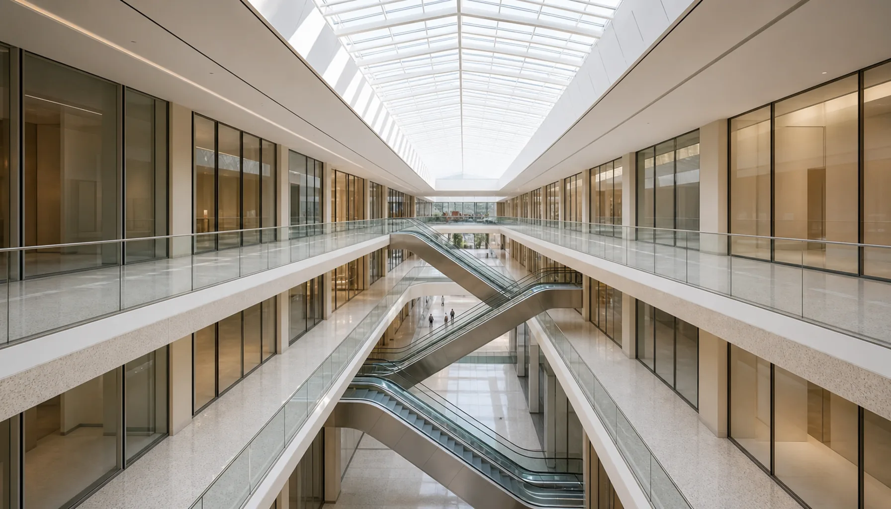 The long atrium seen from the upper gallery — rooflights running the length of the building, escalators crossing the void