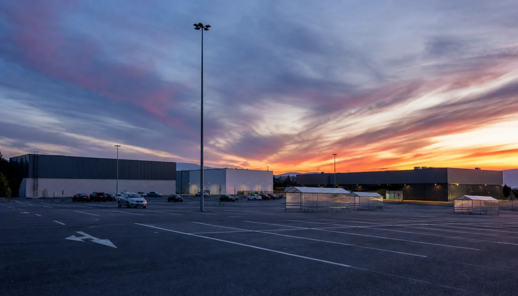 The cluster of large-format units around the shared apron, flat roofs and tall lamp standards under an evening sky