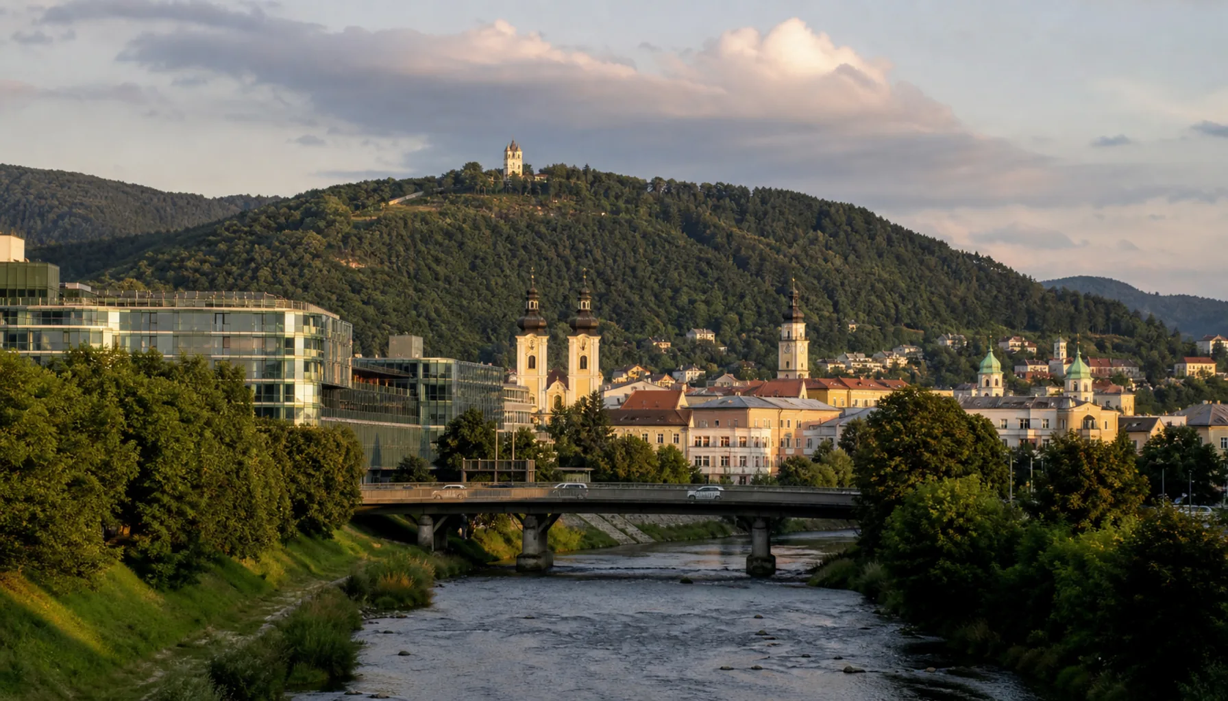 The approach into the centre of Banská Bystrica from the south — the Hron between its embankments, the old-town towers beyond