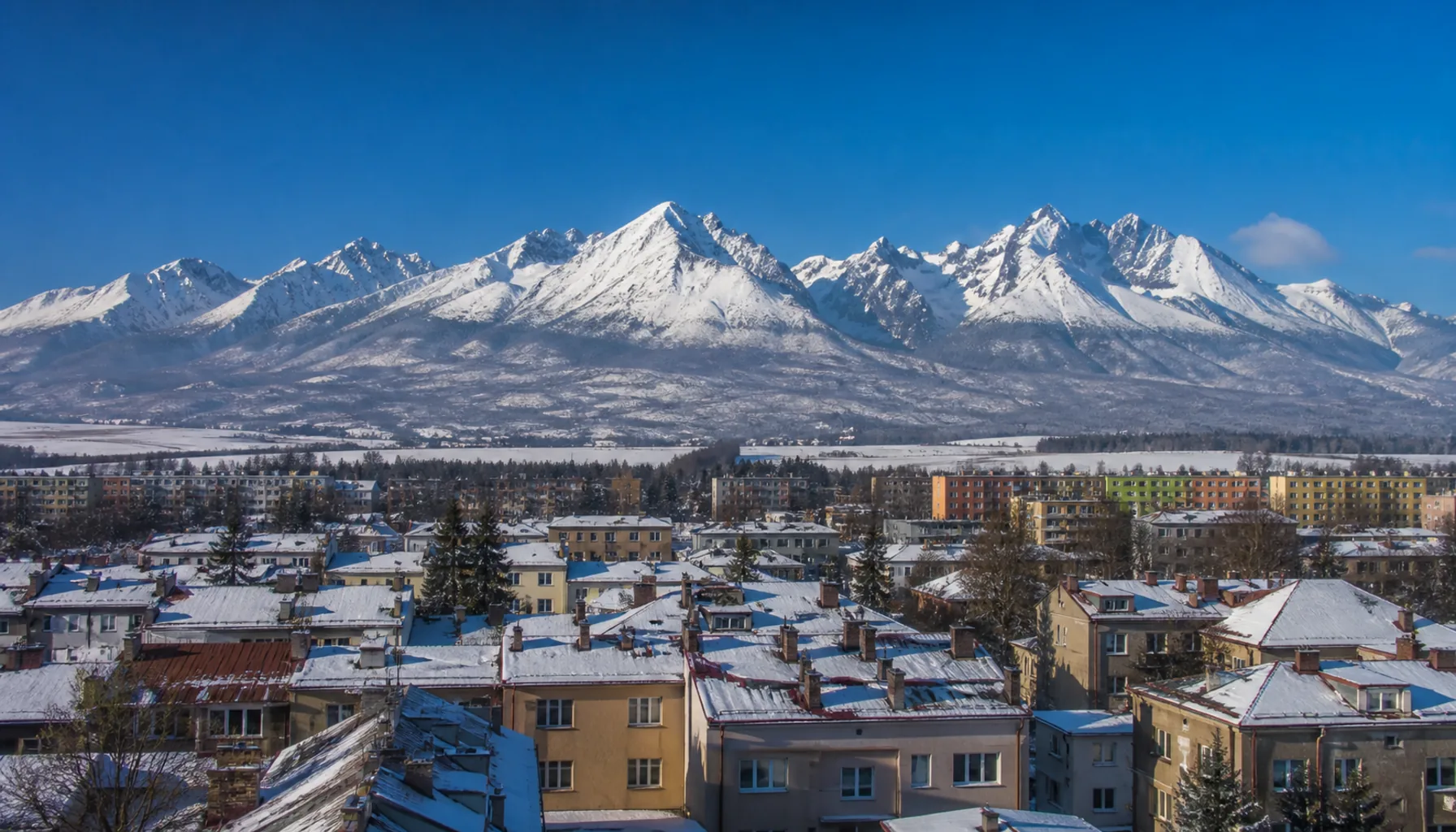 The High Tatras from an upper-floor window above the rooftops of Poprad, snow on the ridges in clear winter light