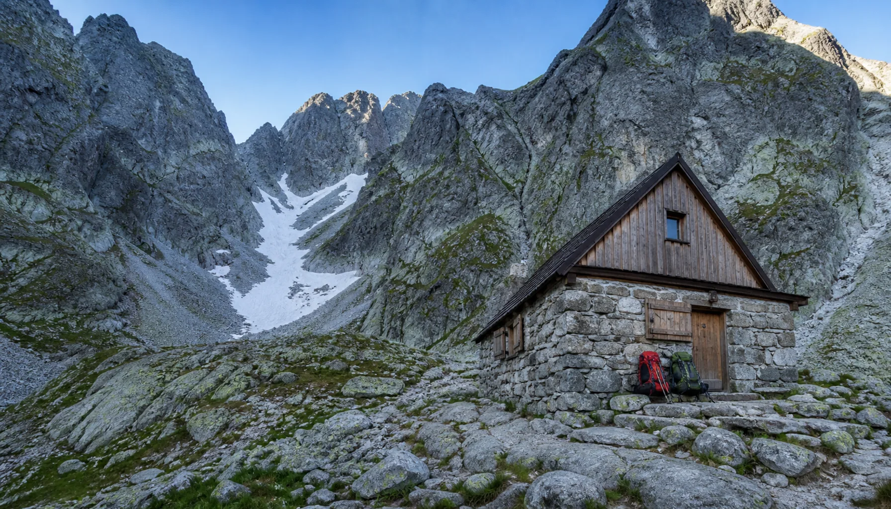 A mountain hut standing on a rocky shelf high beneath the Tatra ridges