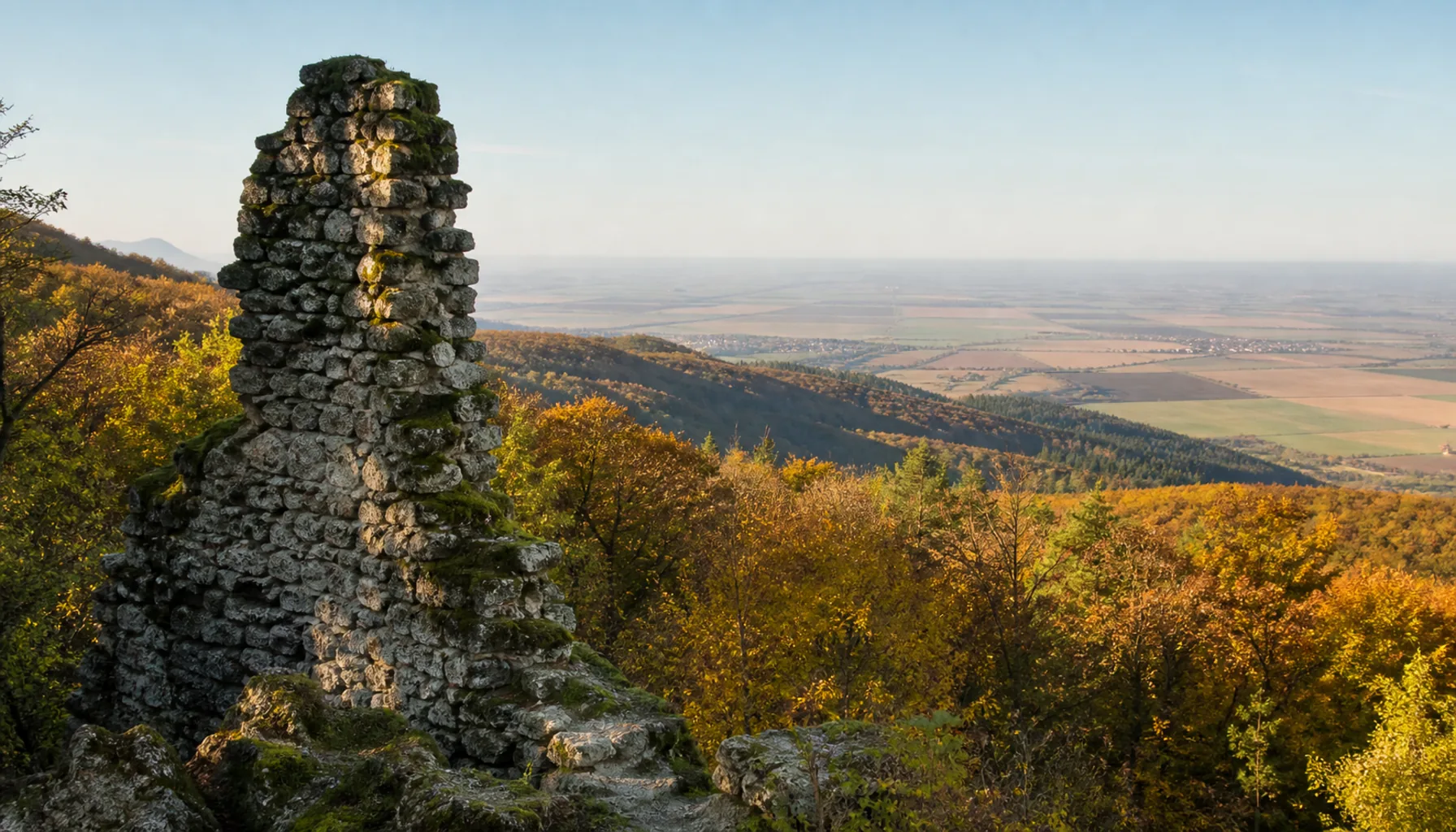 A ruined castle wall on a summit of the wooded Tribeč hills above the Nitra countryside