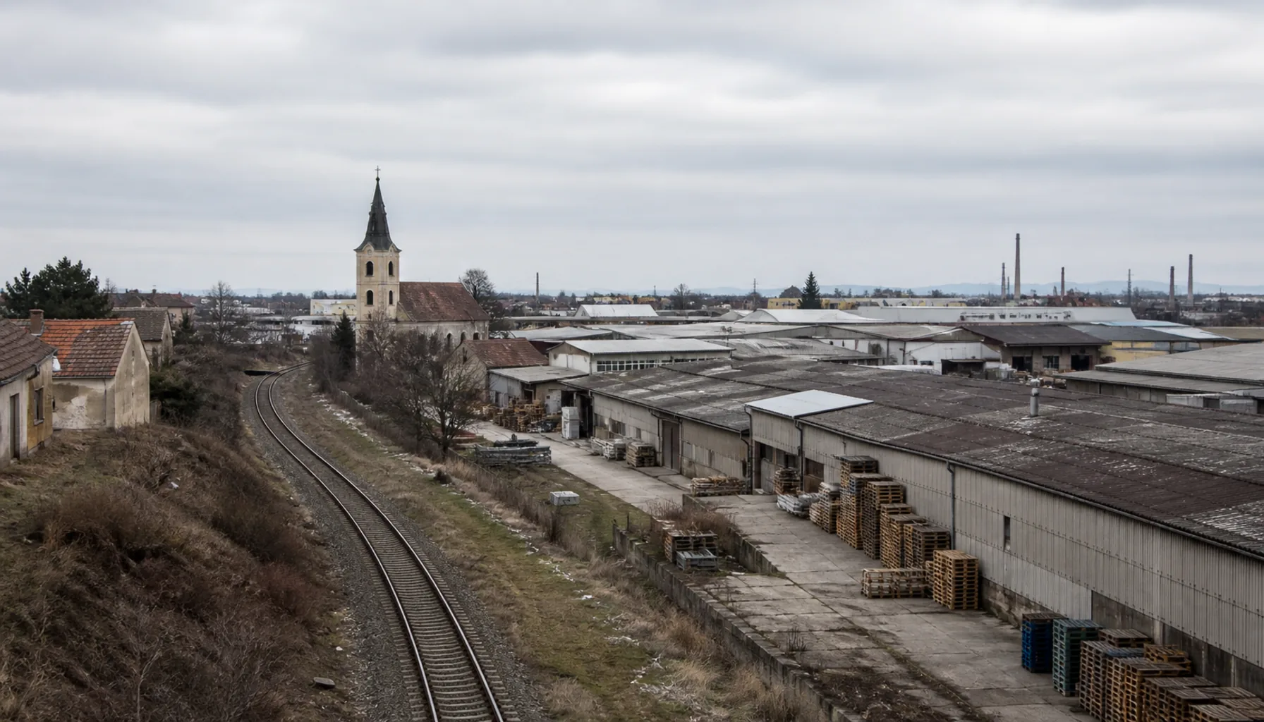 Dolné Krškany — the industrial belt on Nitra’s southern edge, warehouse roofs and rail track running out toward the plain