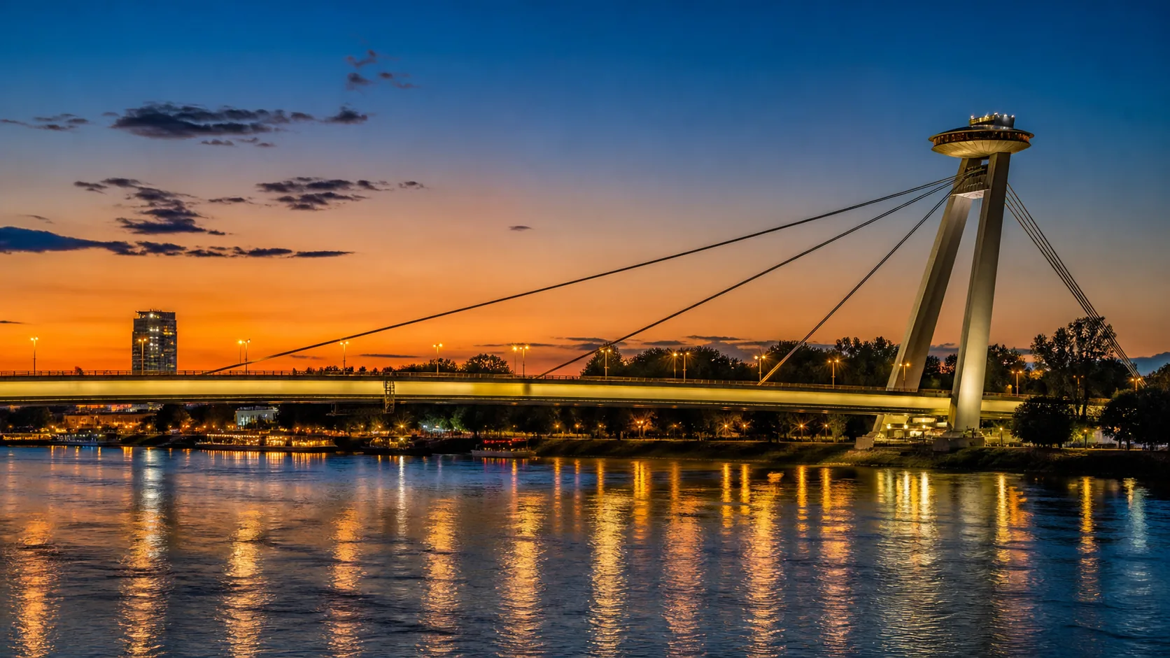 The pylon of the SNP Bridge and its UFO deck over the river at dusk