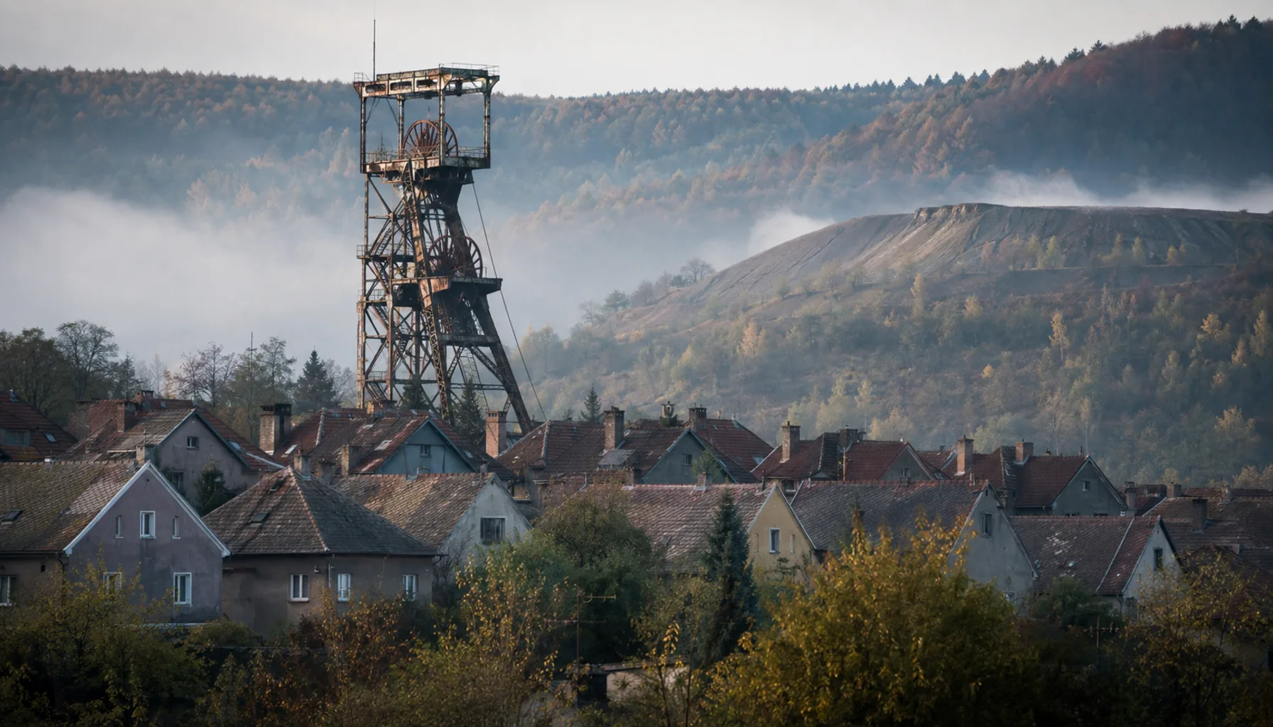 The pit winding tower above Handlová's terraced miners' colony, with the greening spoil heap behind it on an October morning