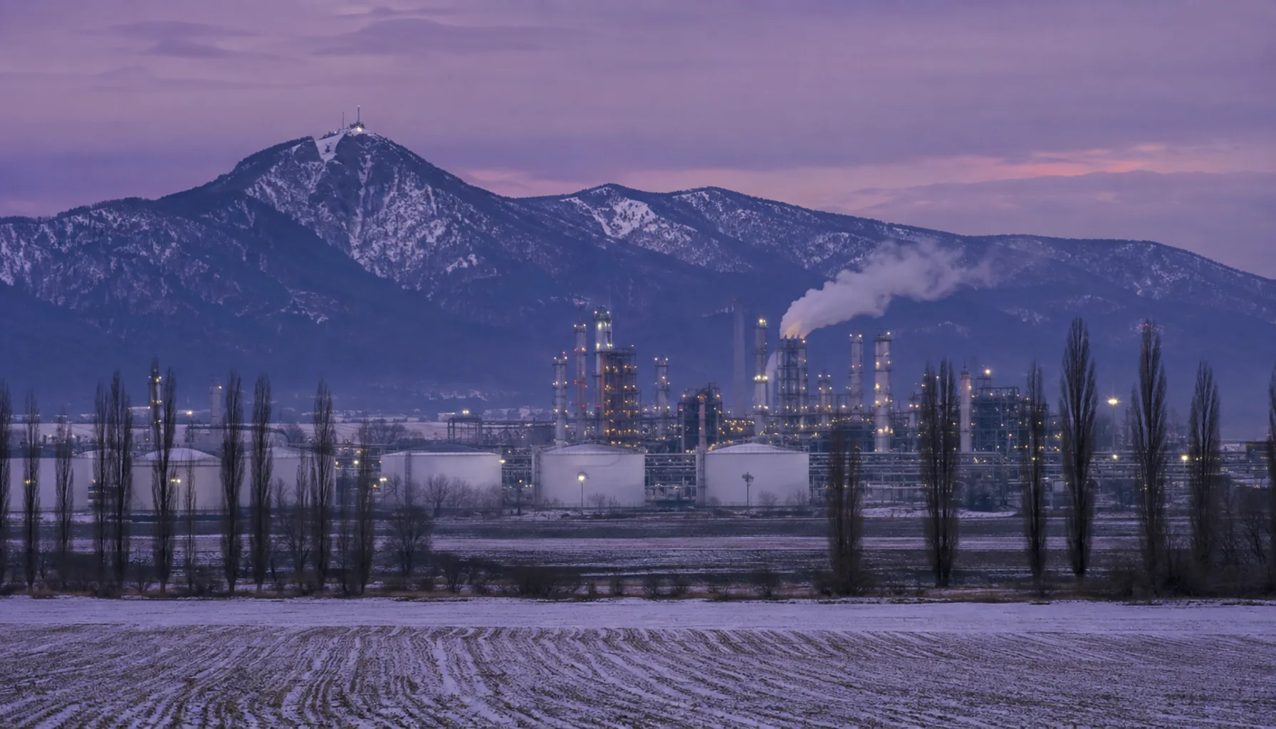 The Nováky chemical works across frozen fields on the upper Nitra, with the volcanic ridge of the Vtáčnik behind, at a December dusk