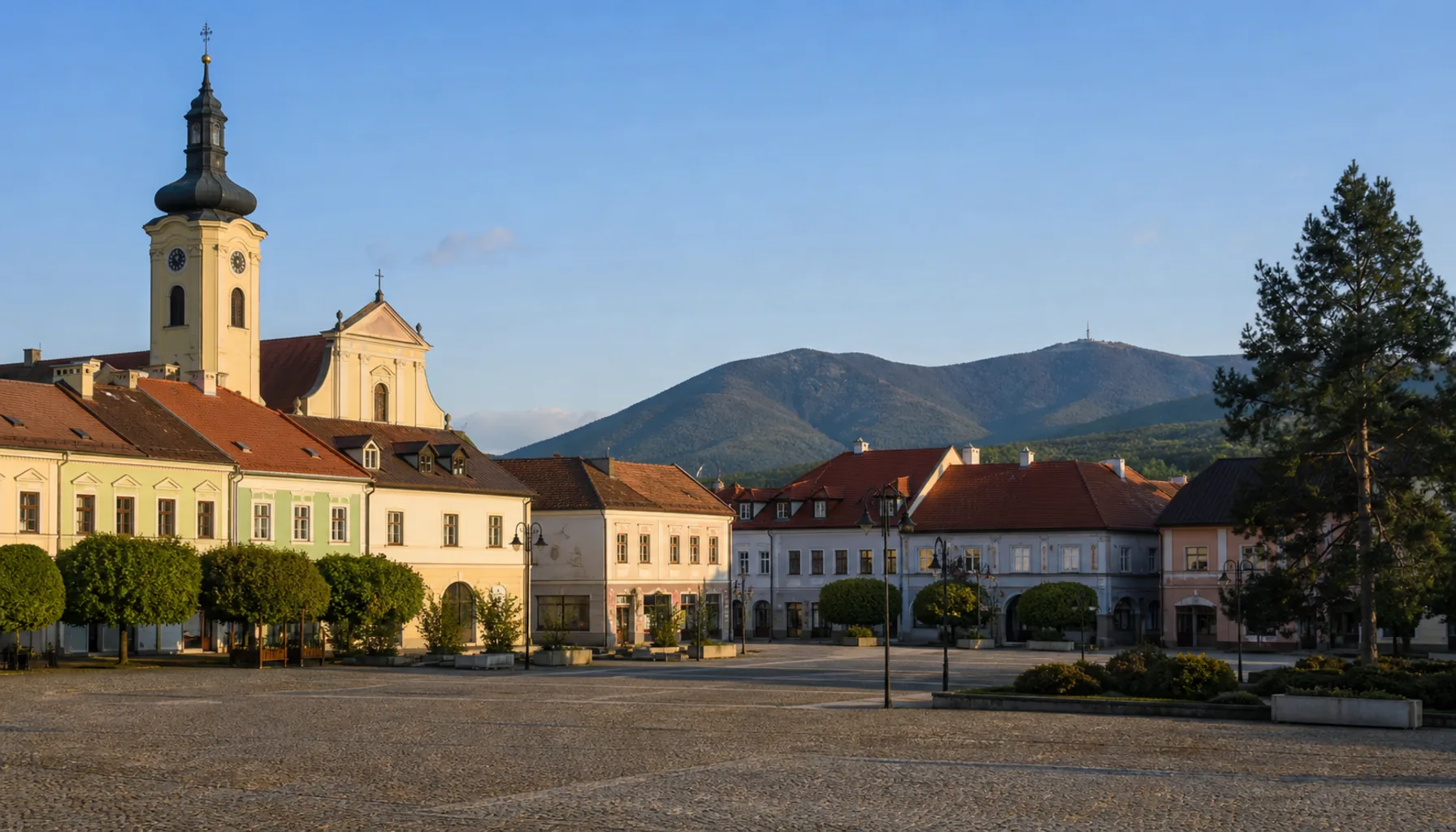 The Baroque tower of the Piarist church on Prievidza's main square, with the Vtáčnik ridge beyond