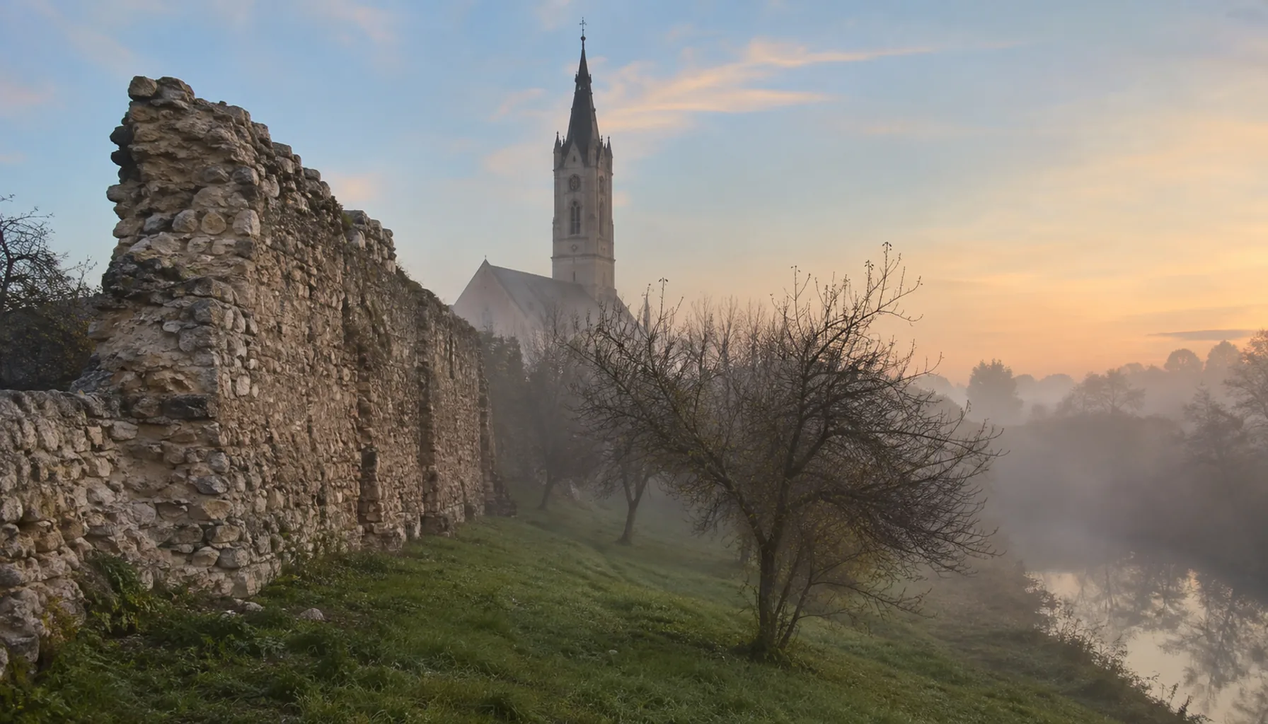 A surviving section of Sabinov's medieval town wall, with the tower of the Gothic parish church behind it