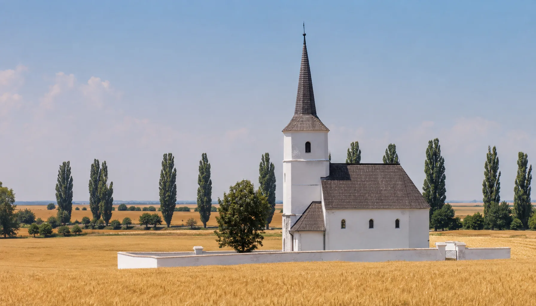 A whitewashed Reformed church with its slender spire above the flat lowland at Veľké Kapušany