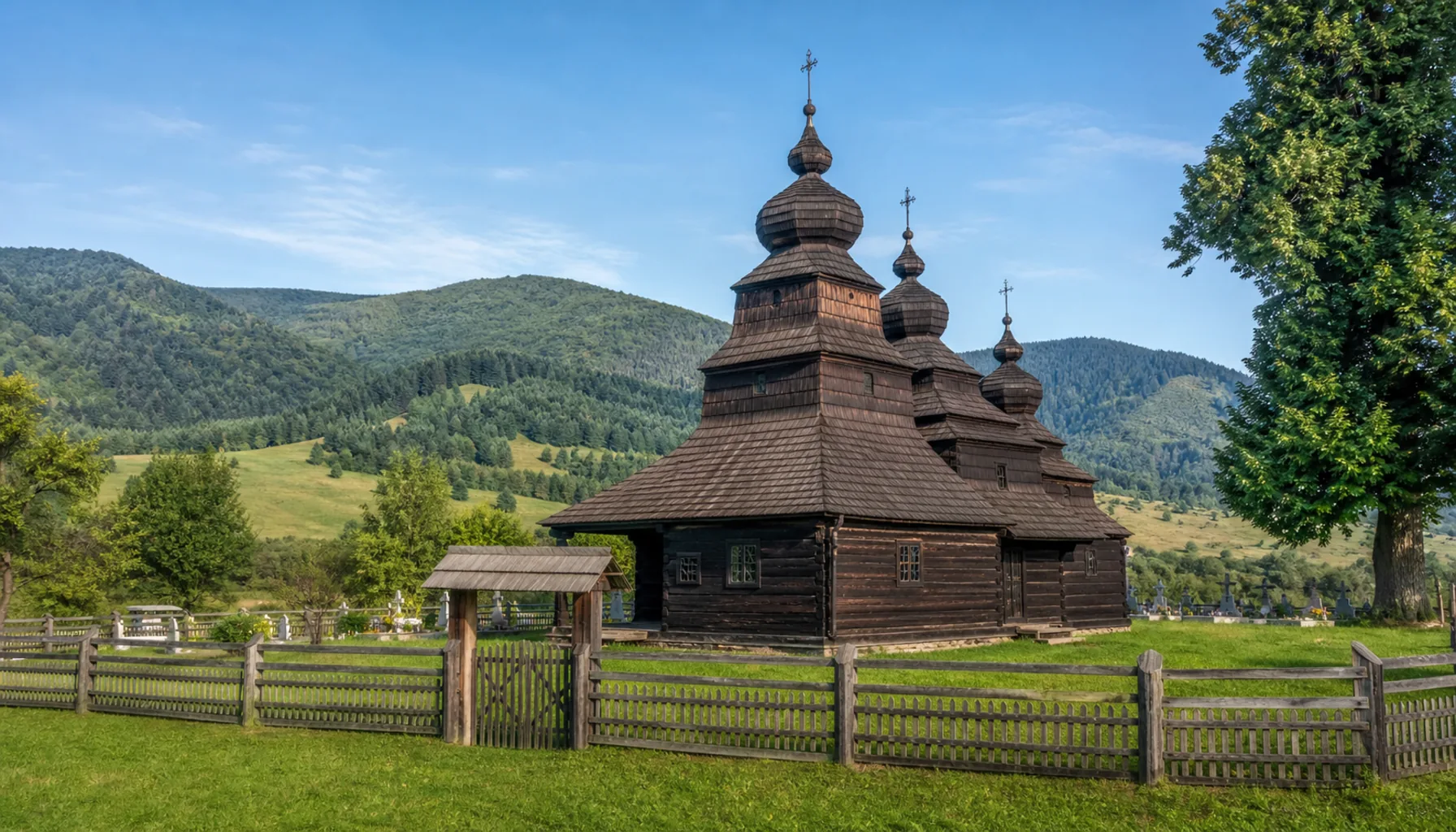 Three shingled towers of the Greek Catholic church of St Nicholas in Bodružal, rising over its churchyard since 1658