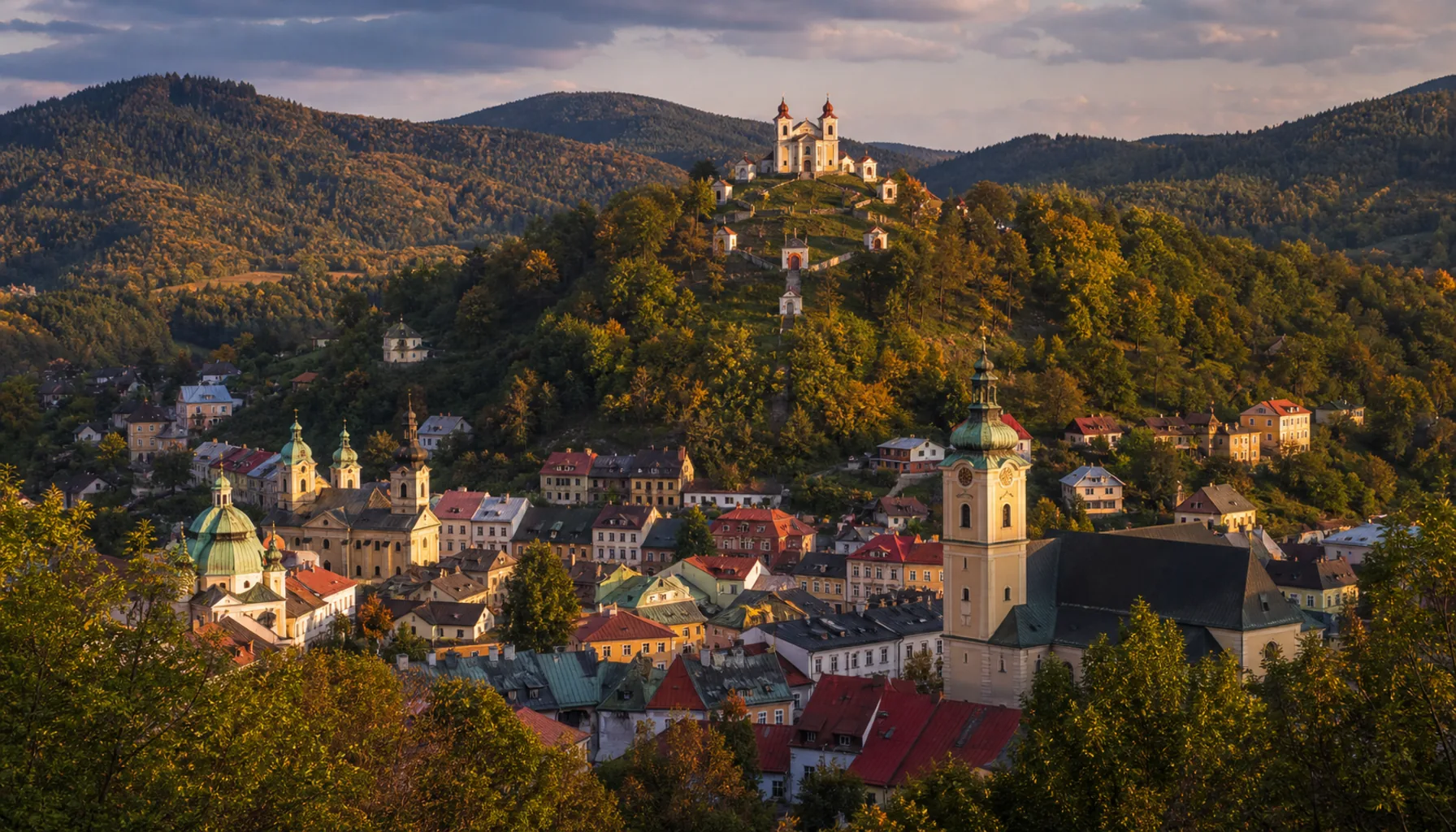 Banská Štiavnica spills down its volcanic caldera, the Calvary rising on the wooded hill above the mining town