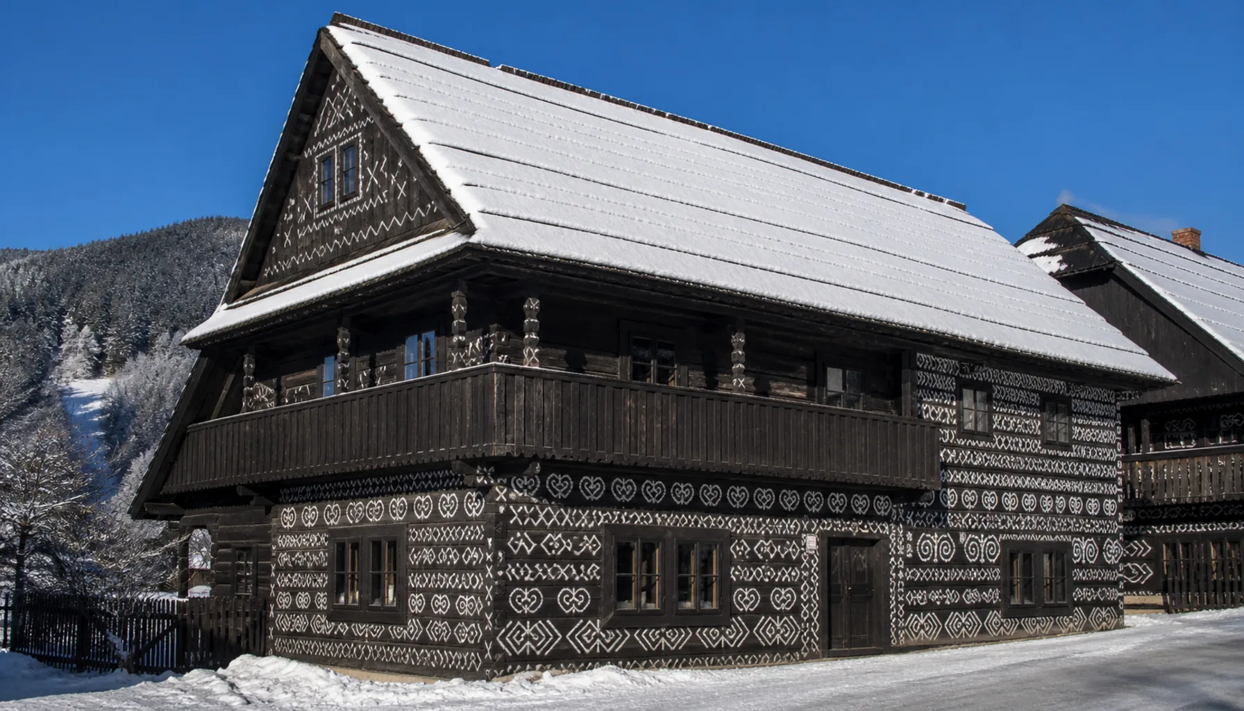 White lime patterns drawn over the dark log gable of a house at Čičmany